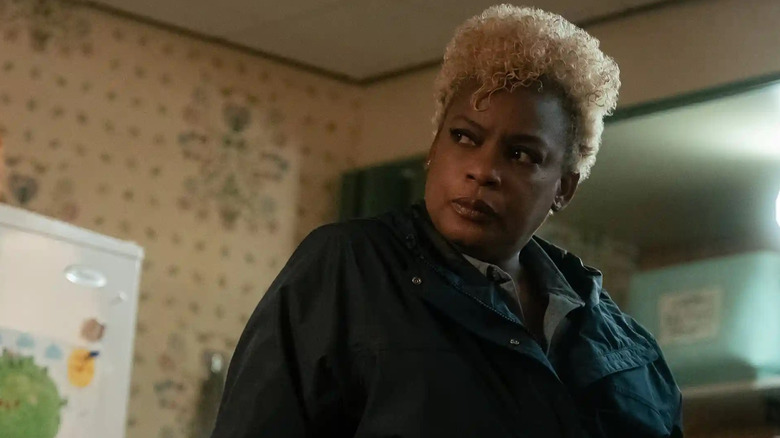 Agent Rand standing in a kitchen in "Lucky" (2026)
