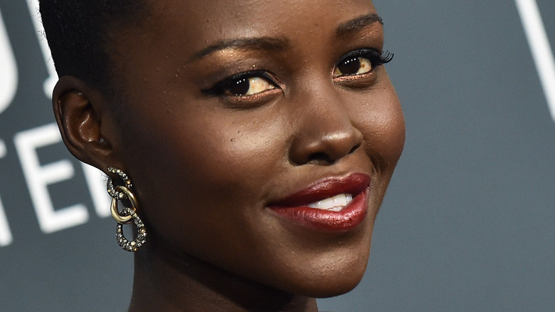 Lupita Nyong'o smiling in earrings