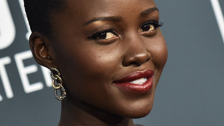 Lupita Nyong'o wearing diamond earings and red lipstick