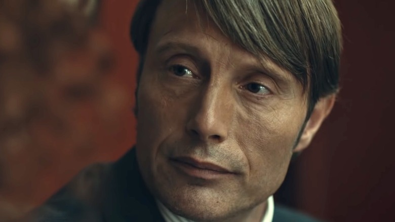 Mads Mikkelsen as Hannibal in front of red wall