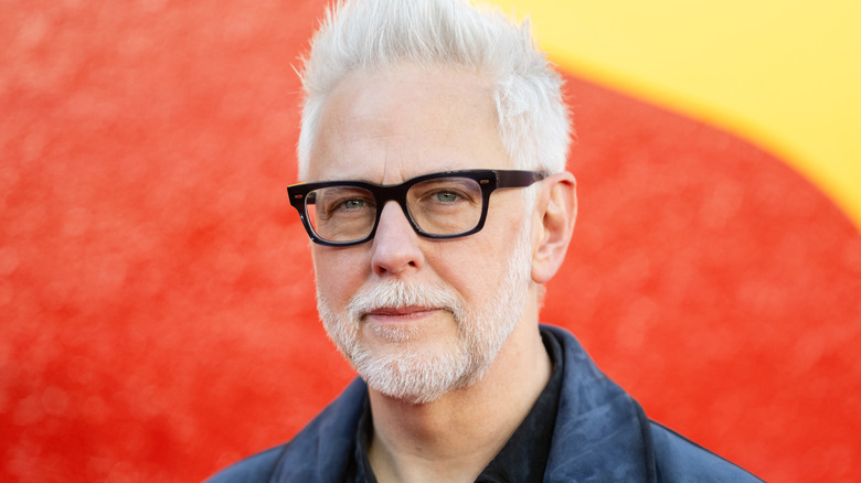 James Gunn posing in front a Superman logo at a fan event in London