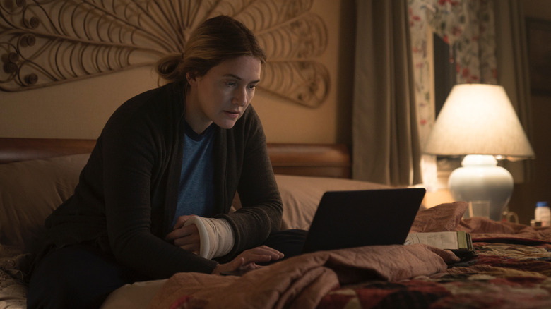 Mare sits in bed working on her laptop in "Mare of Easttown" (2021)