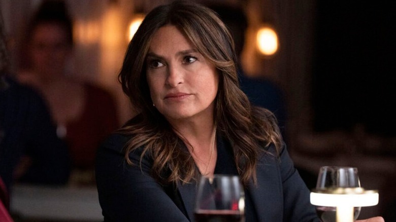 Olivia looking at someone sitting at a bar with a glass of wine in front of her on Law and Order Special Victims Unit