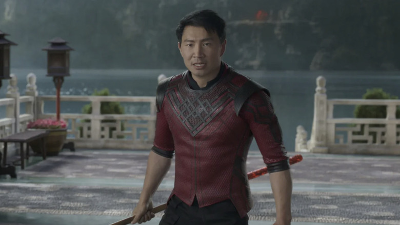 Shang-Chi stands in a temple wielding a weapon in "Shang-Chi and the Legend of the Ten Rings" (2021)