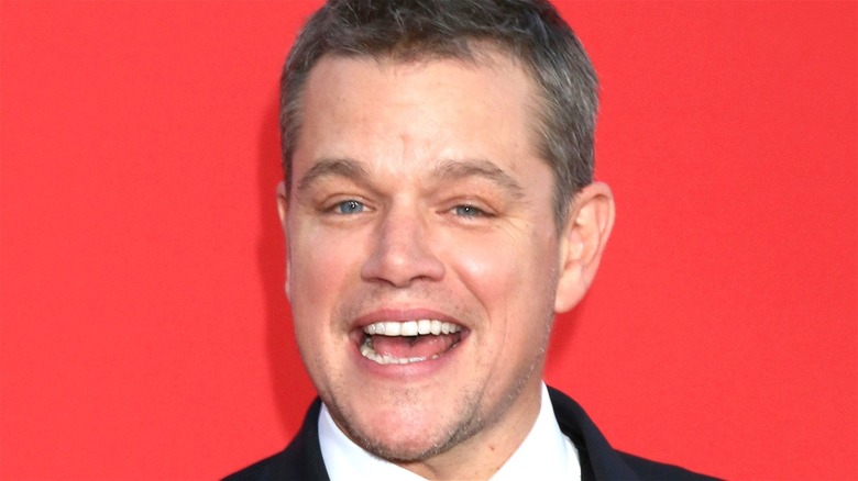 Matt Damon smiling red background