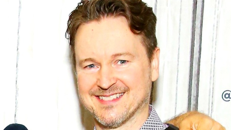 Matt Reeves smiling in front of a white background