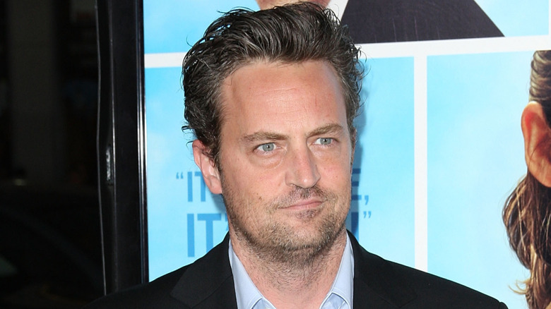 Matthew Perry wearing a black suit