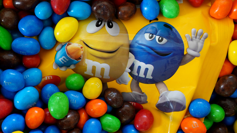 A package of peanut M&M's piled with peanut M&M's on top of it