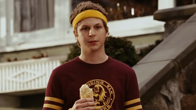 Michael Cera in jogging attire holds a hot pocket