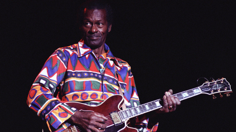 Chuck Berry playing guitar against a black background