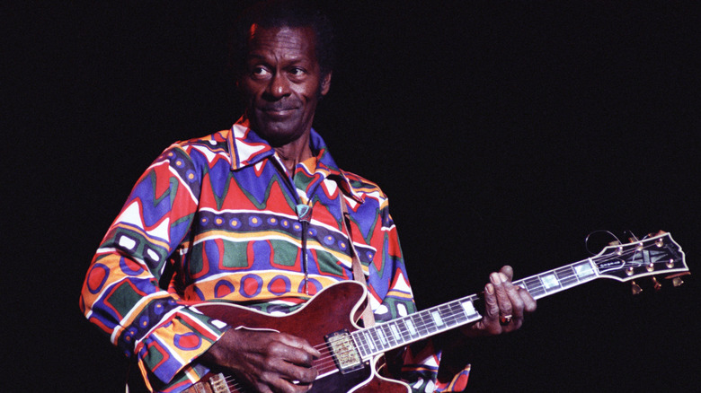 Chuck Berry playing guitar against a black background