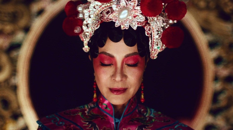 One of Evelyn's alternate selves wearing ornate finery and dramatic makeup with her eyes closed