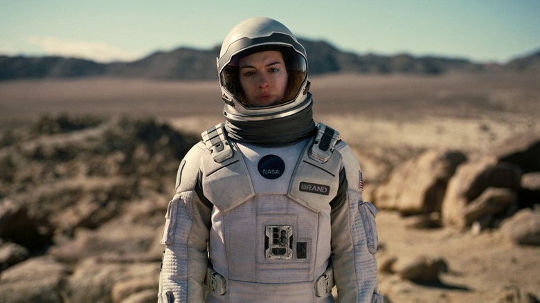 Astronaut Brand standing on rocky, desert-like terrain in her spacesuit