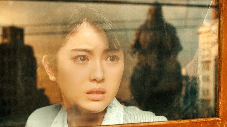Noriko Oishi looking at Godzilla through a window (2023)