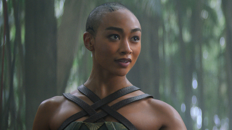 Jade stands in a forest in 