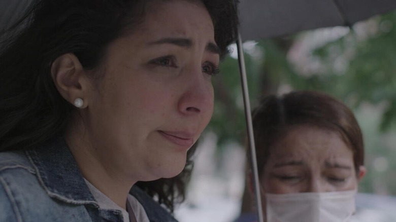 A woman crying under an umbrella in Stolen Youth: Inside the Cult at Sarah Lawrence