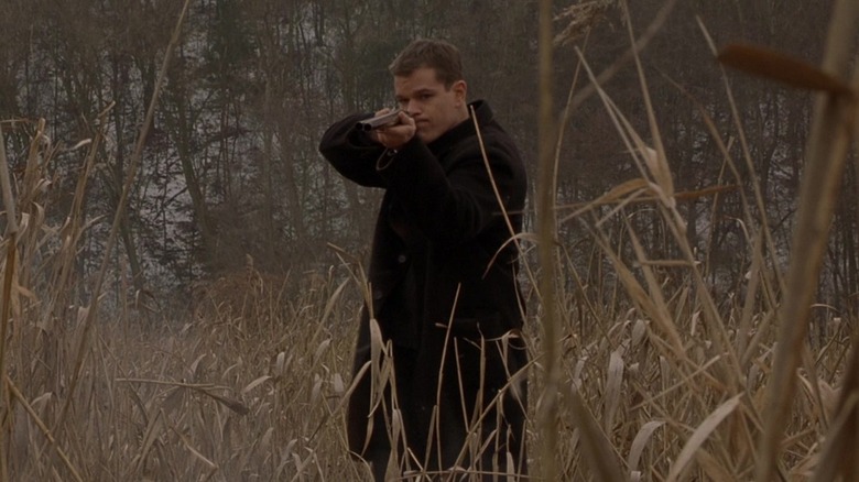 Jason Bourne holding gun in grass