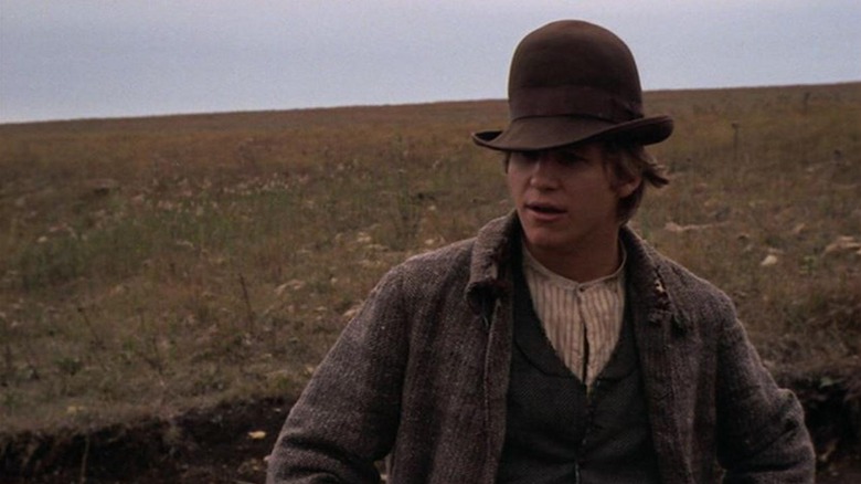 Jake Rumsey stands in a crevice wearing a large domed hat in Bad Company (1972)