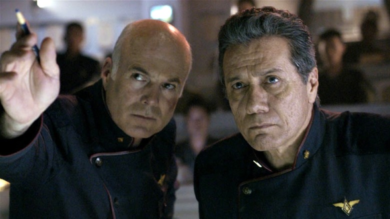 Saul Tigh and Commander Adama leaning in to look at something