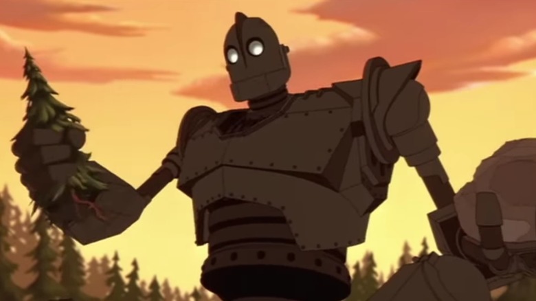 The giant holds up a tree and a rock in The Iron Giant