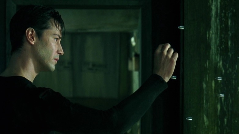 Neo reaches out a hand toward bullets suspended in mid air in The Matrix