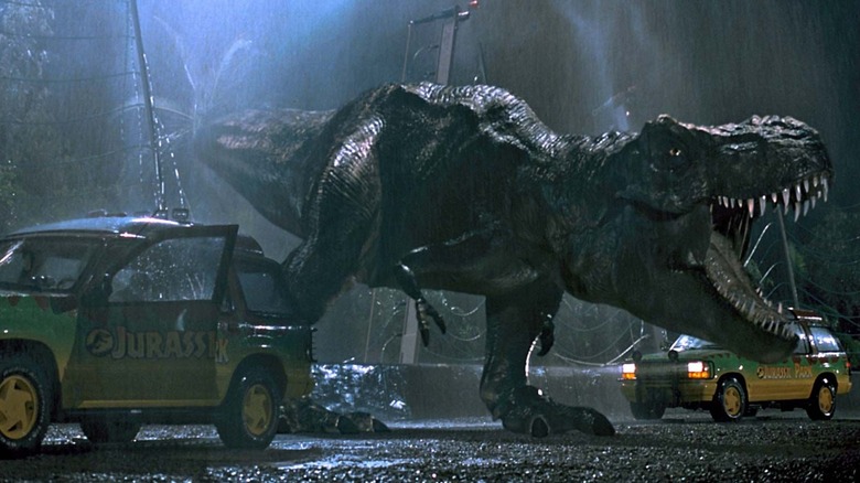 A Tyrannosaurus rex roaring in "Jurassic Park" beside two Jeeps