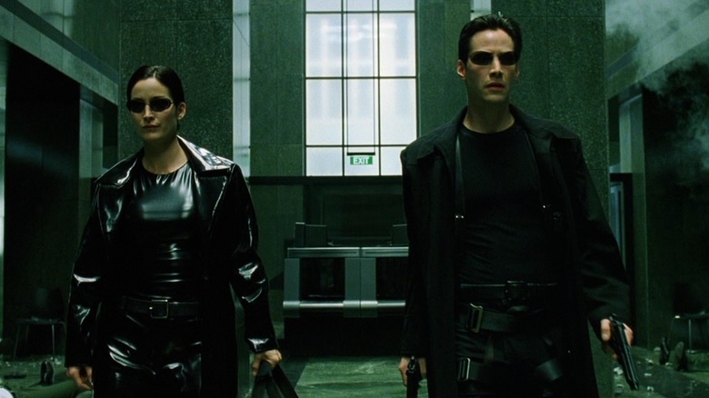 Trinity and Neo walking through a lobby in "The Matrix" after shooting the place up
