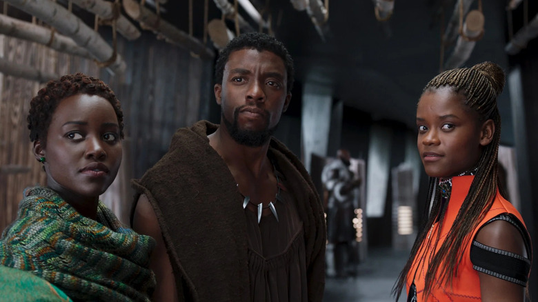 Nakia, T'Challa, and Shuri standing together in a dark hallway