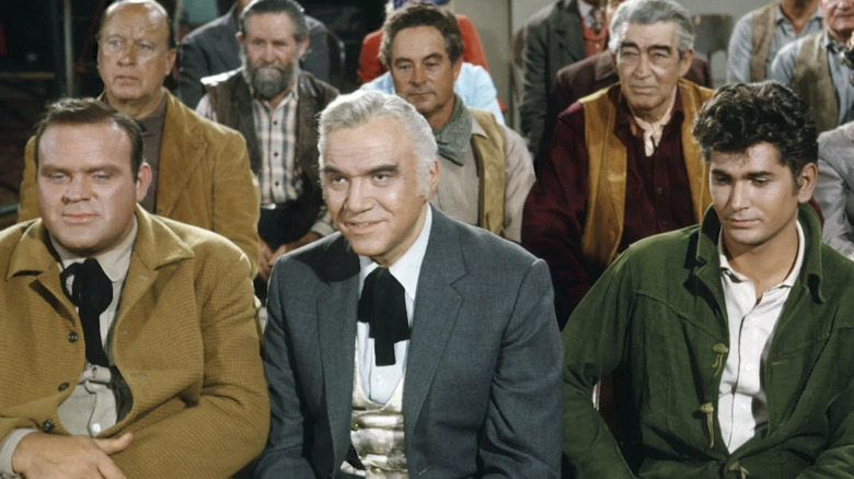 Hoss, Ben, and Joe Cartwright sit in an audience on Bonanza (1959-1973)