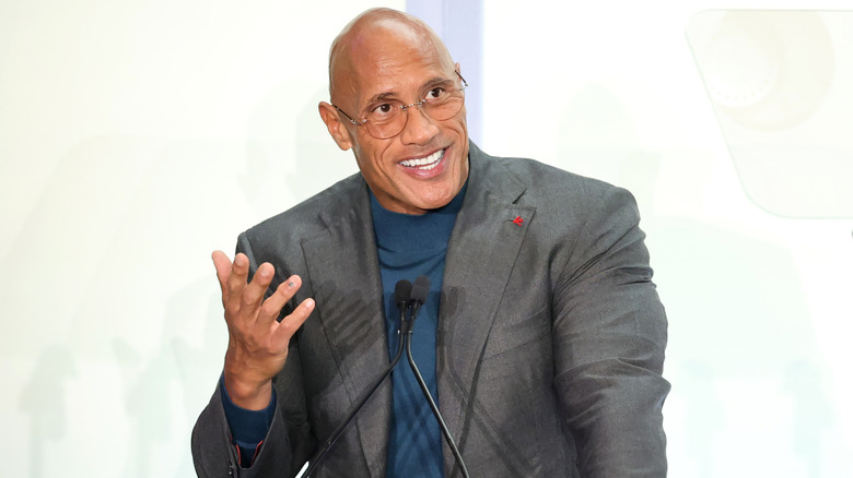 Dwayne Johnson smiling and gesturing in front of a microphone