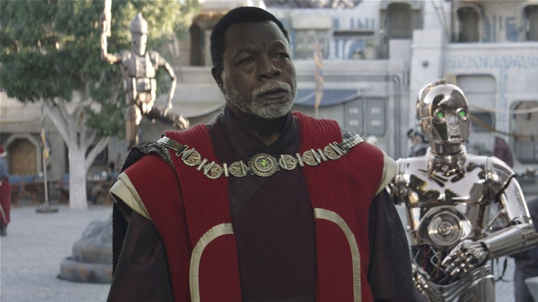 Greef Karga standing in front of and Nevarro copper droid