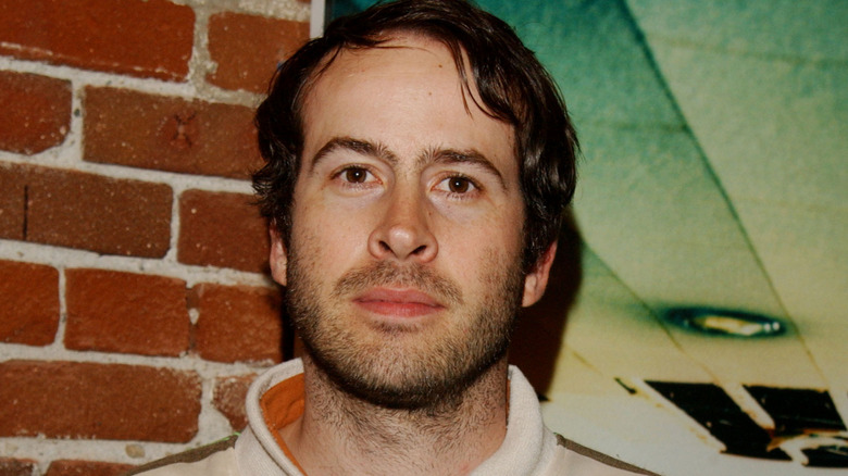 Jason Lee in front of a brick wall with a picture hanging on it