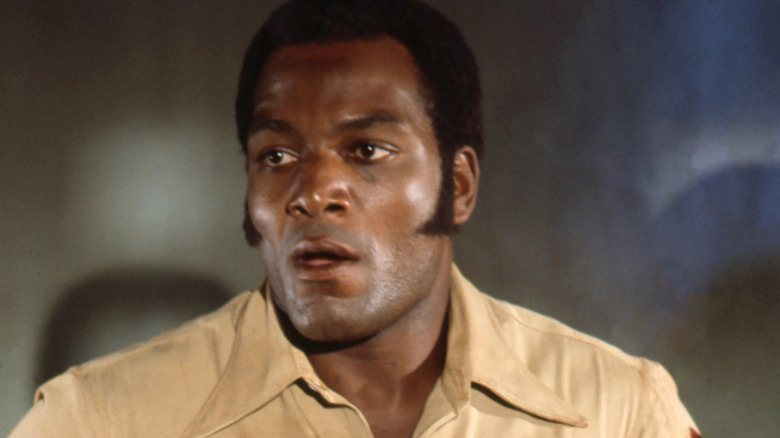 Jim Brown with sideburns wearing a tan shirt
