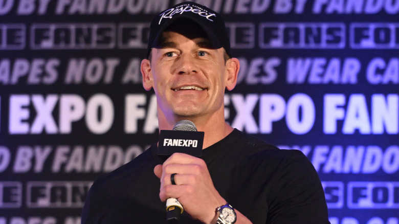 John Cena smiling and holding a microphone