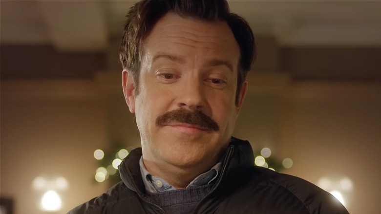 Ted looking down with a grin in Ted Lasso Season 4