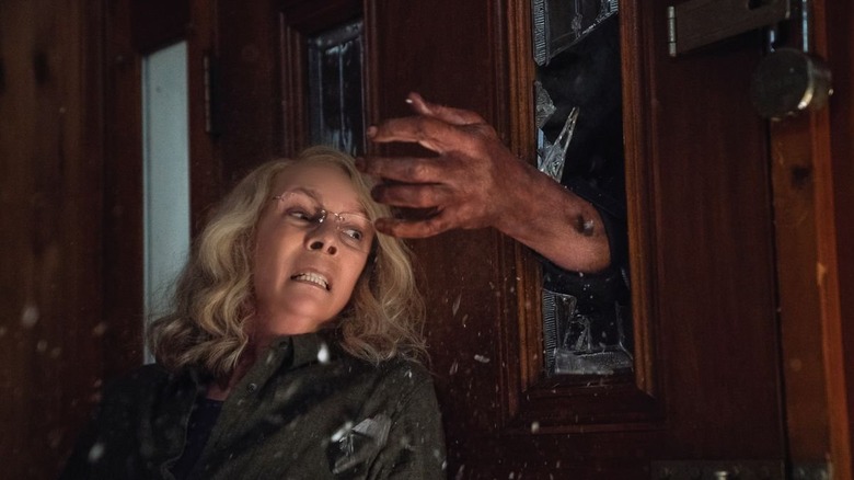Michael reaches through a door for Laurie in "Halloween" (2018)