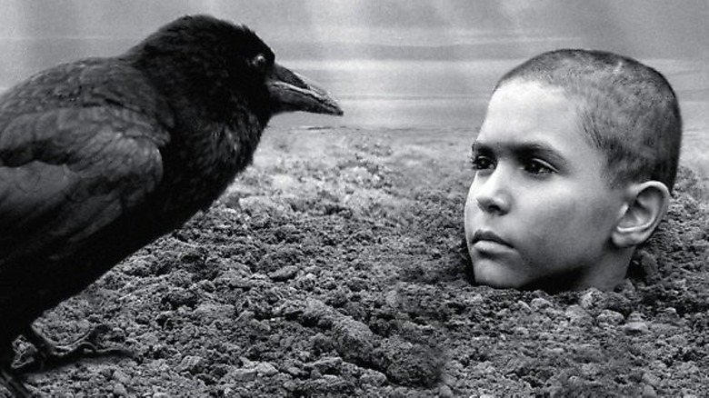A crow eyes the buried boy