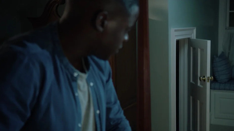 Chris looks suspiciously at a small door under the stairs in "Get Out" (2017)