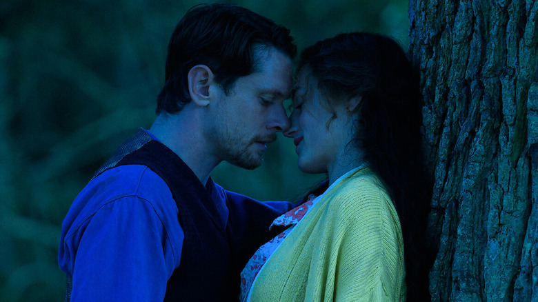 Connie and Oliver prepare to kiss against a tree in "Lady Chatterley's Lover" (2022)