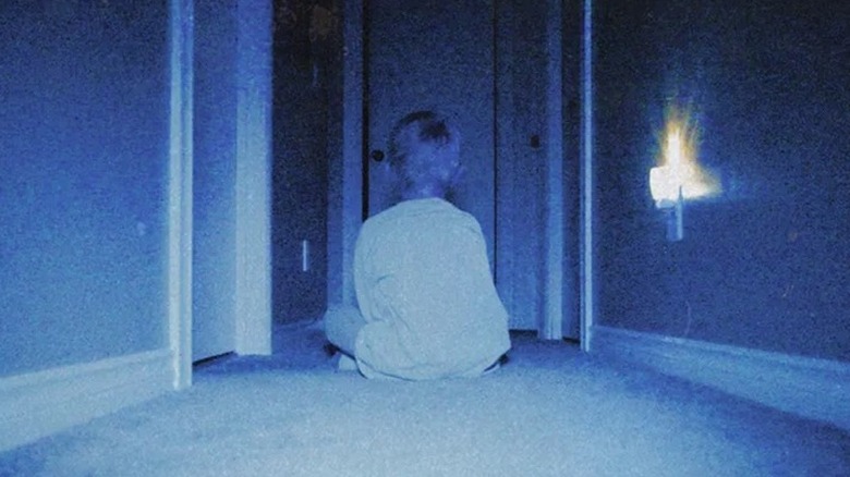 Kevin sitting in the middle of the floor facing away in "Skinamarink" (2022)