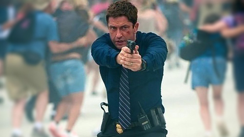 Mike aims a gun while civilians flee behind him in "Olympus Has Fallen" (2013)