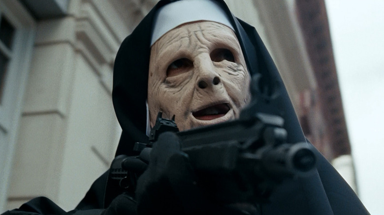 A robber dressed as a nun aims a machine gun in "The Town" (2010)