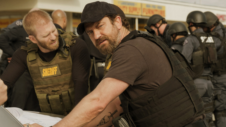 Nick looking at document against car in "Den of Thieves" (2018)