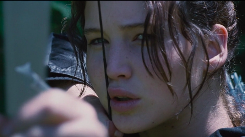Katniss aims her bow and arrow during The Hunger Games