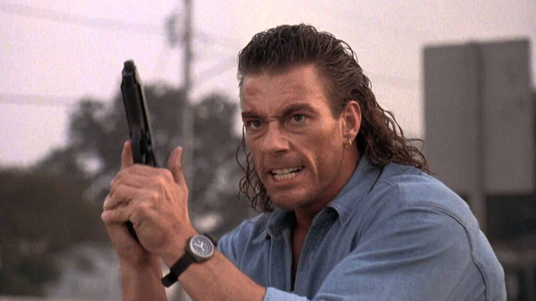 Chance Boudreaux with wet hair gritting his teeth and holding up a pistol in Hard Target