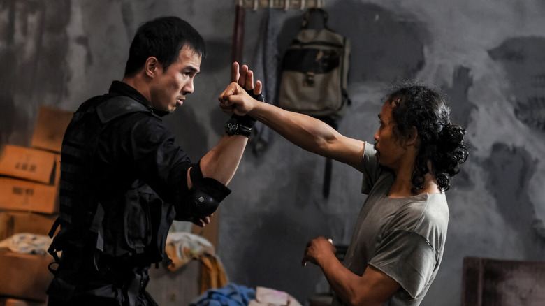 Rama blocking a punch from Mad Dog while wearing black tactical SWAT gear in The Raid: Redemption