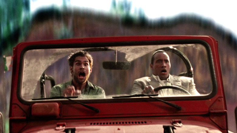 Beck driveing a Jeep down a hill as Travis screams in the passenger seat in "The Rundown"