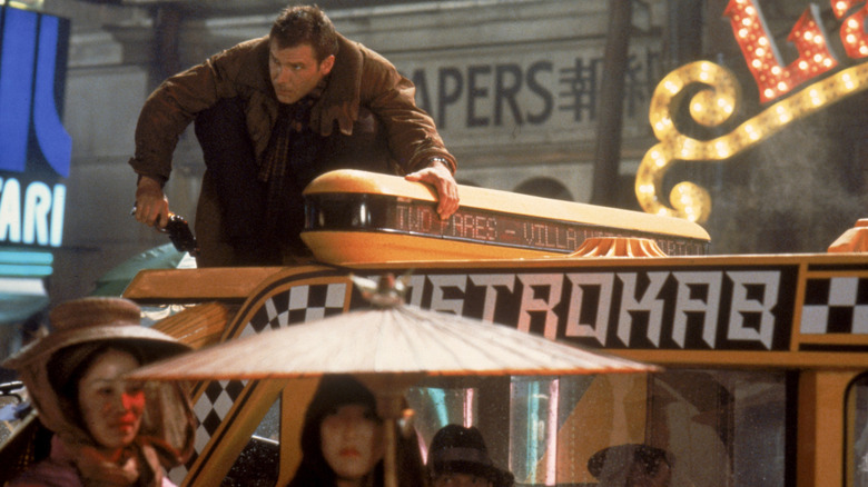 Decker squatting on top of a taxi in Blade Runner (1982)
