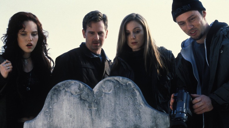 Teens standing over a grave with a camera in Book of Shadows: Blair Witch 2 (2000)