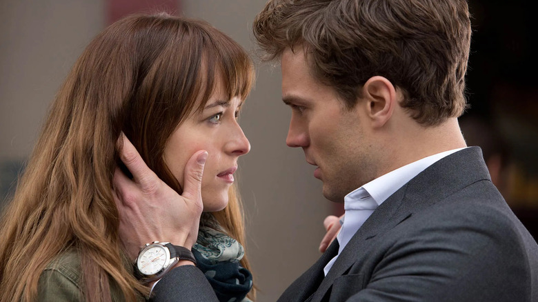 Jame Dornan holds Dakota Johnson's face in profile